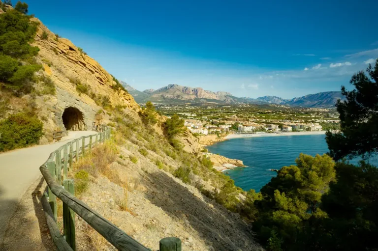Vista panorámica desde la ruta del Faro del Albir, con el túnel excavado en la roca y el mar Mediterráneo al fondo junto a la bahía de Altea.