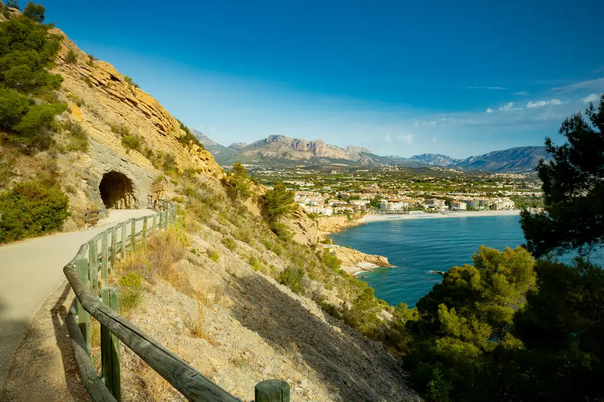 Vista panorámica desde la ruta del Faro del Albir, con el túnel excavado en la roca y el mar Mediterráneo al fondo junto a la bahía de Altea.