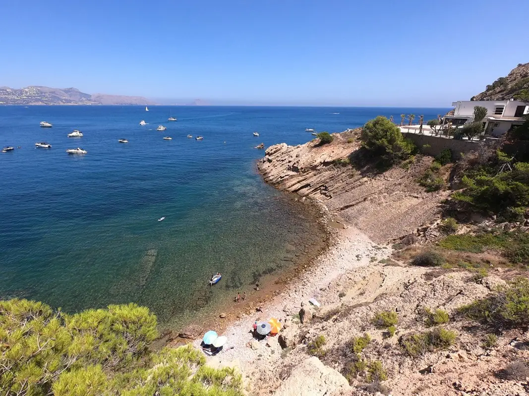 Vista panorámica de la Cala del Amerador en El Albir con aguas cristalinas y entorno rocoso del Parque Natural Serra Gelada.