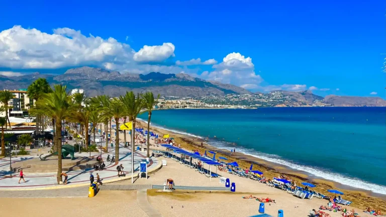 Vista panorámica de la Playa del Albir en verano con arena, sombrillas y mar azul