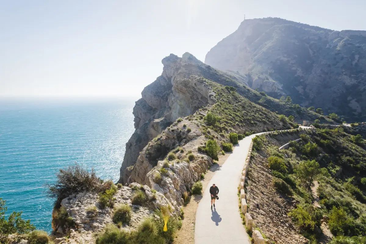 Senderista caminando por la ruta del Faro del Albir con vistas al mar Mediterráneo.