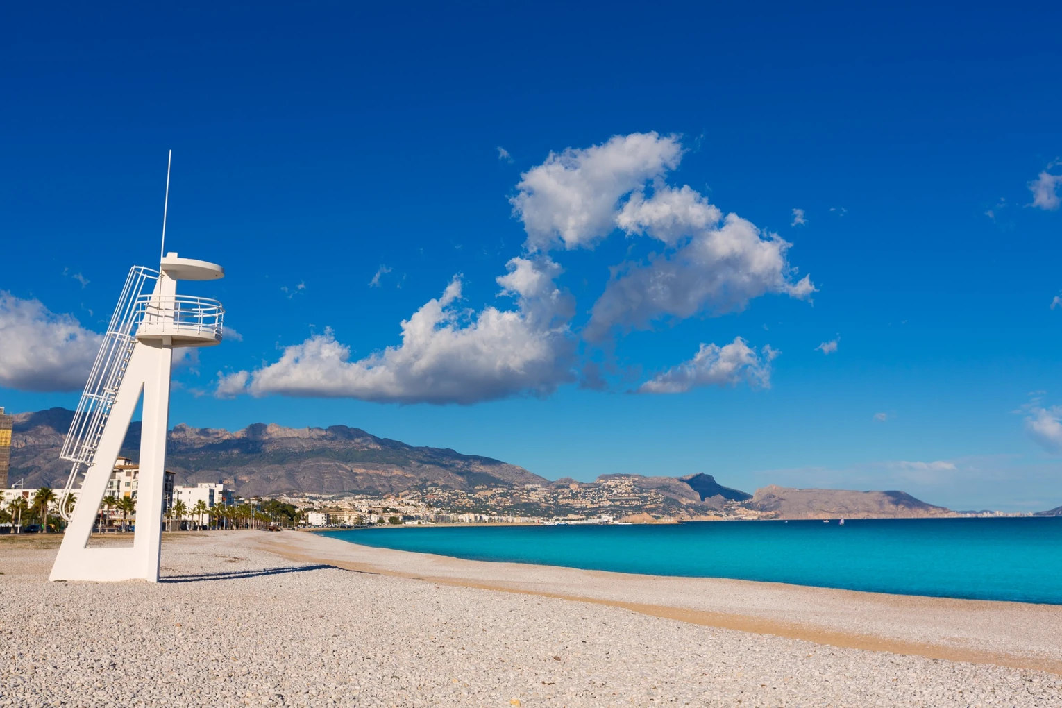 La Playa del Albir en un día tranquilo, con el Mediterráneo en calma y la Serra Gelada de fondo.