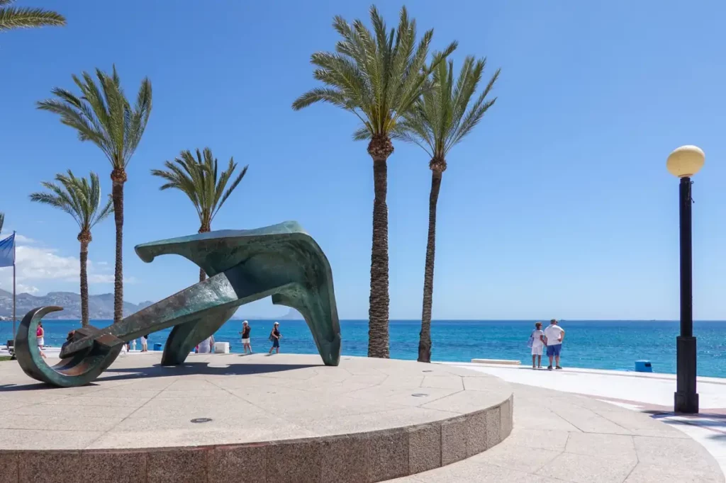 Sculpture on El Albir promenade with palm trees and Mediterranean Sea in the background